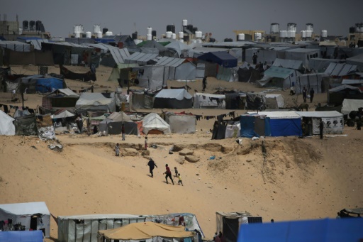 Des Palestiniens marchent dans un camp de personnes déplacées à Rafah, dans le sud de la bande de Gaza, près de la frontière avec l'Egypte, le 28 avril 2024