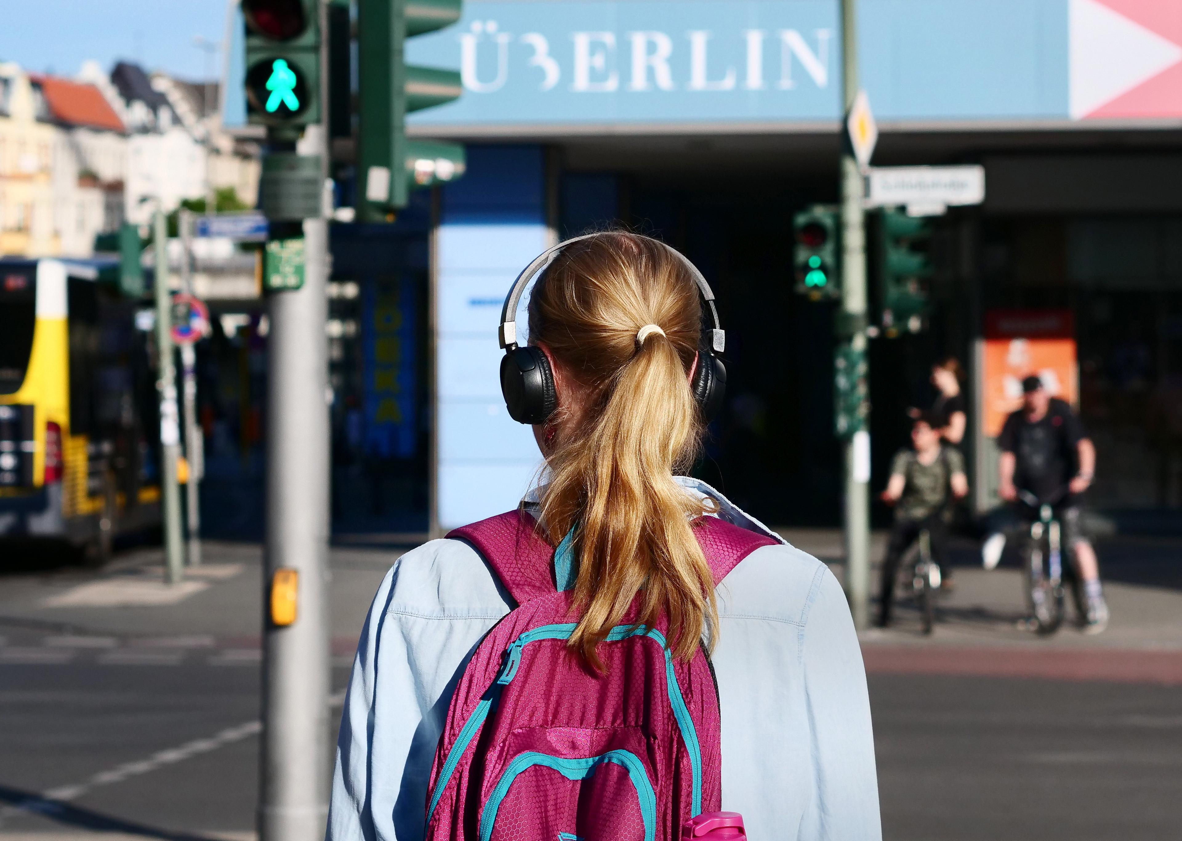 Mädchen geht mit Kopfhörern über die Straße