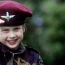 William looks into the camera and salutes while in an army uniform in 1986.