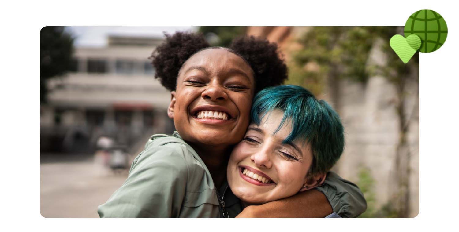 Two young girls smiling while hugging each other.