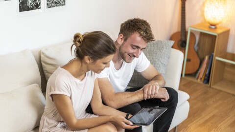 Una coppia di persone su un divano sta osservando un tablet