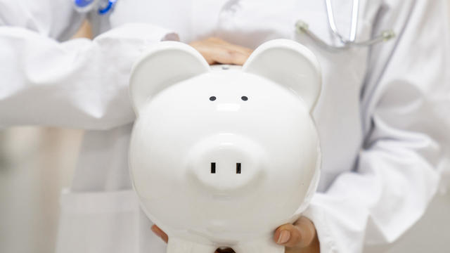 Doctor holding a piggybank at the hospital - health insurance 