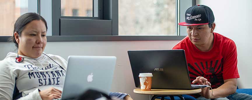 A Native American female and a Native American male student with their laptops