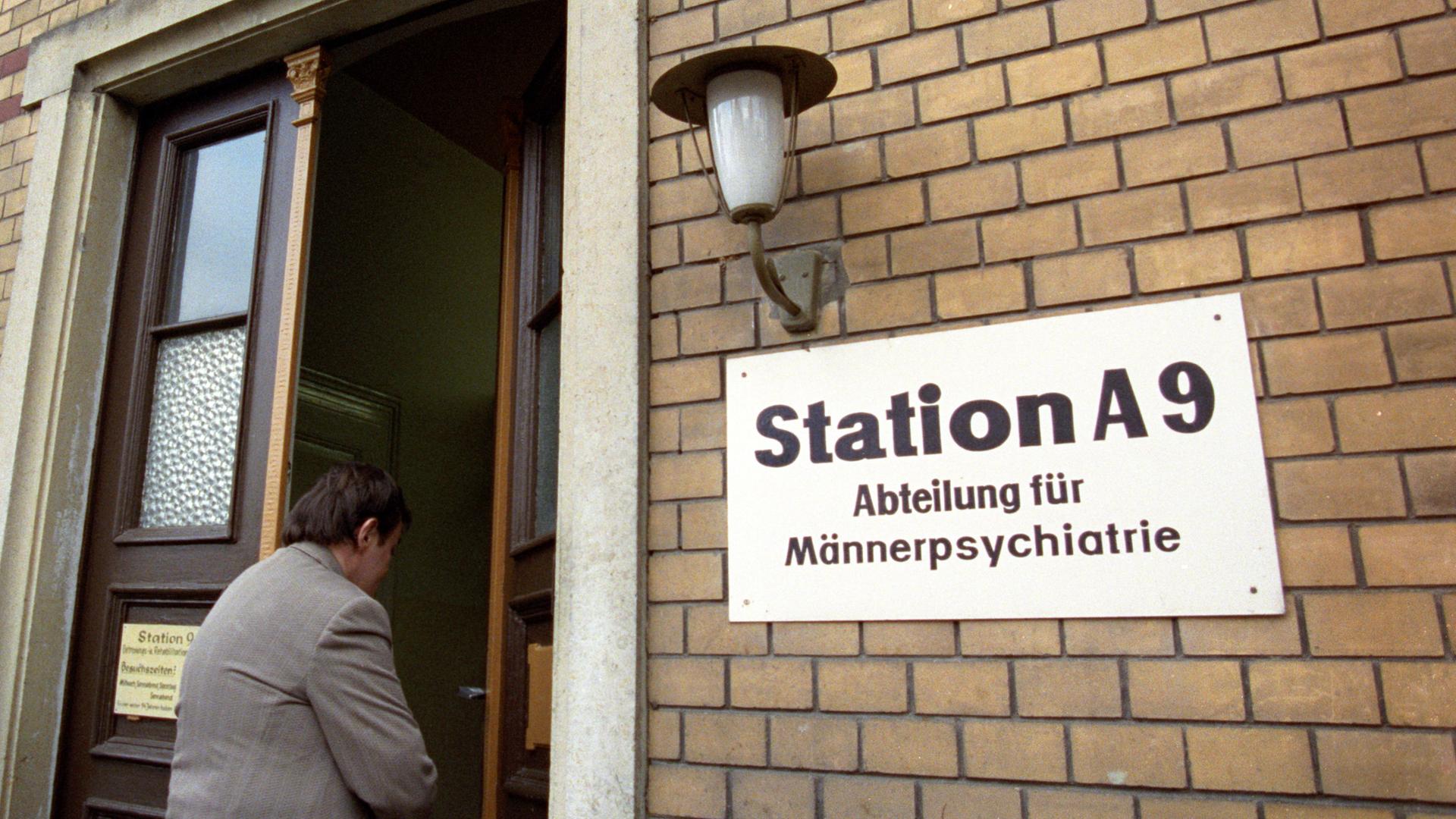 Neben der Eingangstür eines Backsteingebäudes hängt ein Schild mit der Aufrschrift "Station A9 - Abteilung für Männerpsychiatrie".