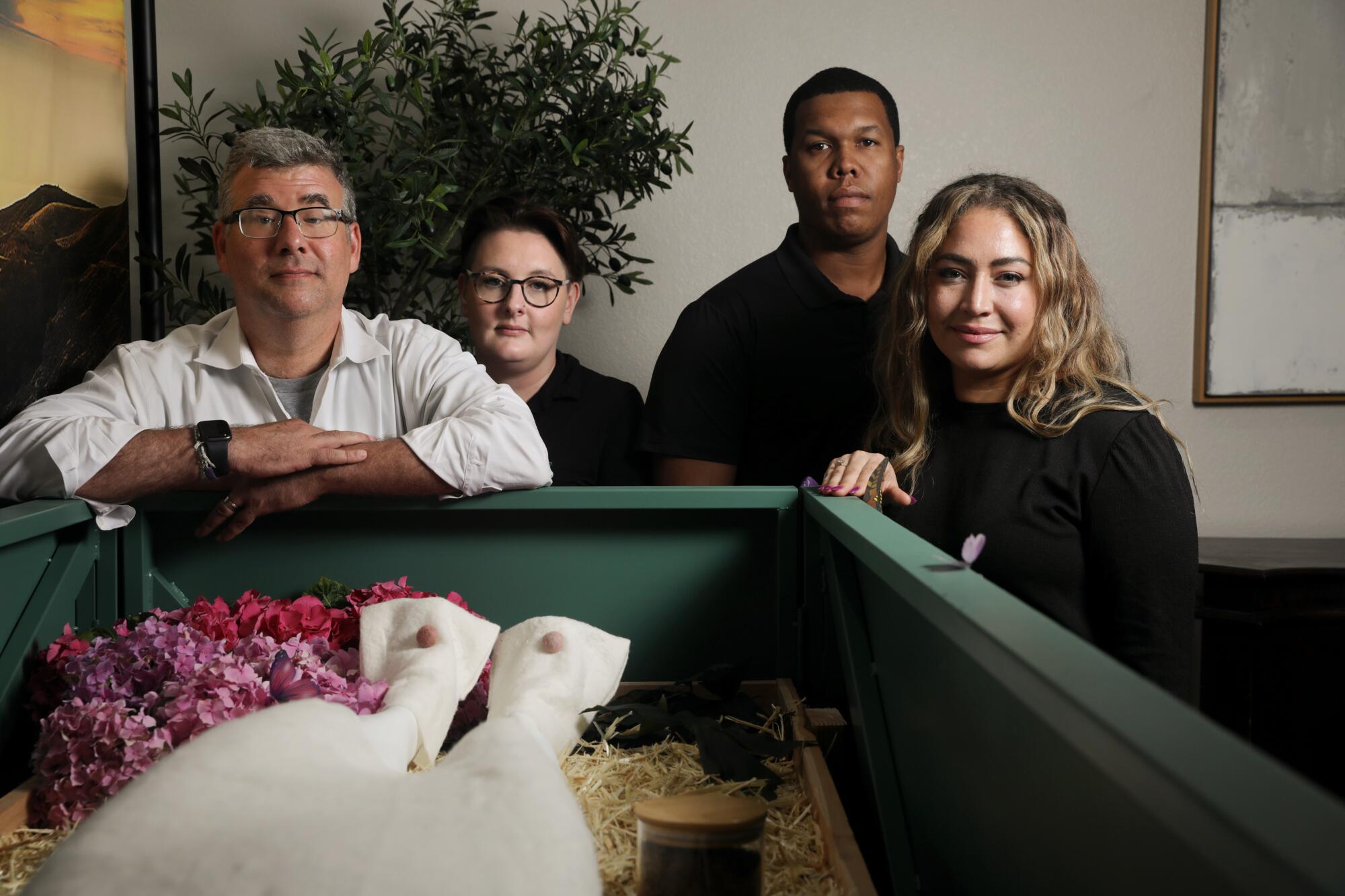 Micah Truman, Katey Houston, Lauren Williams and Chris Brown stand over a mannequin in a casket.