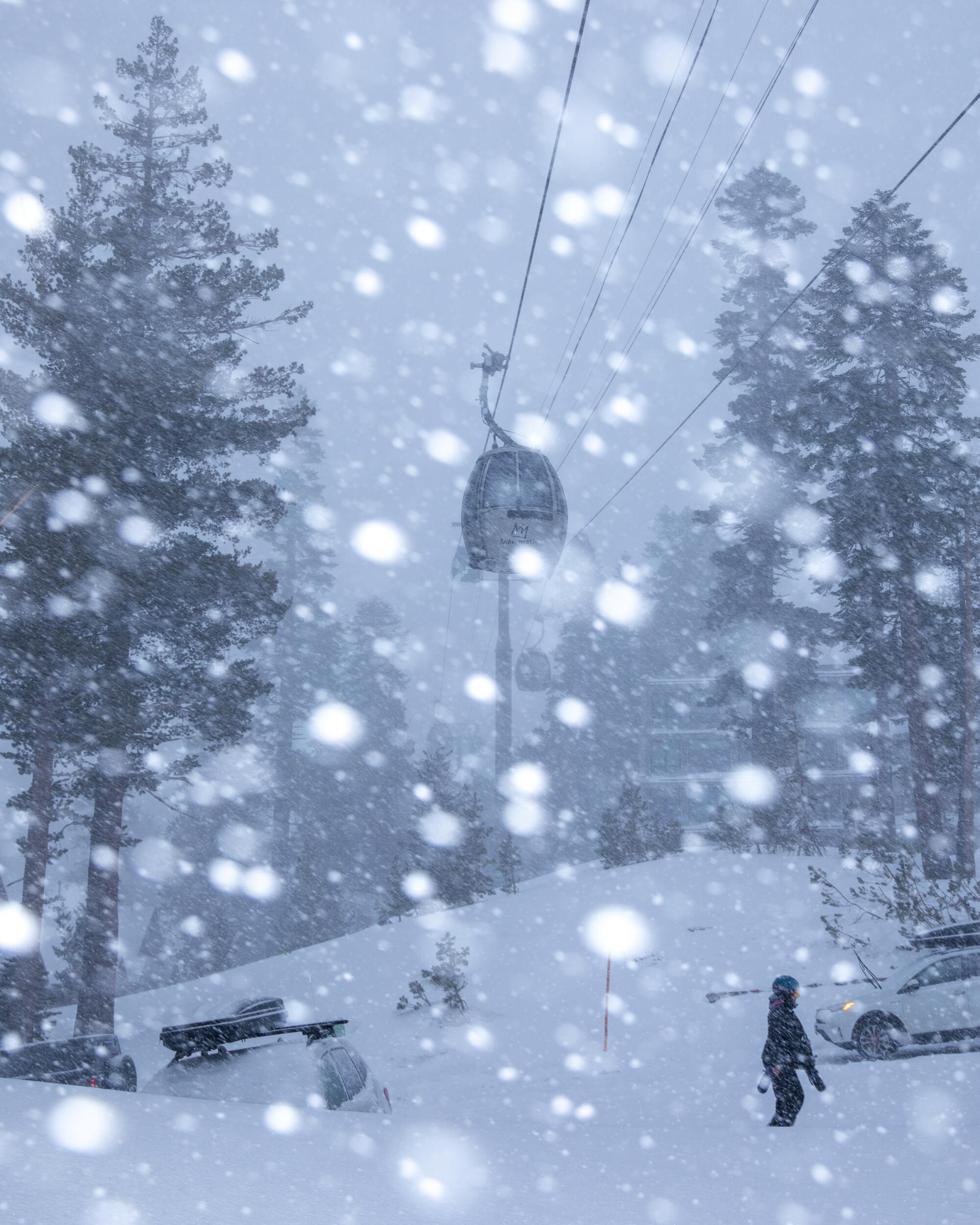 Snow falls on a scene of one person, pine trees, snow-covered ground and an aerial lift.