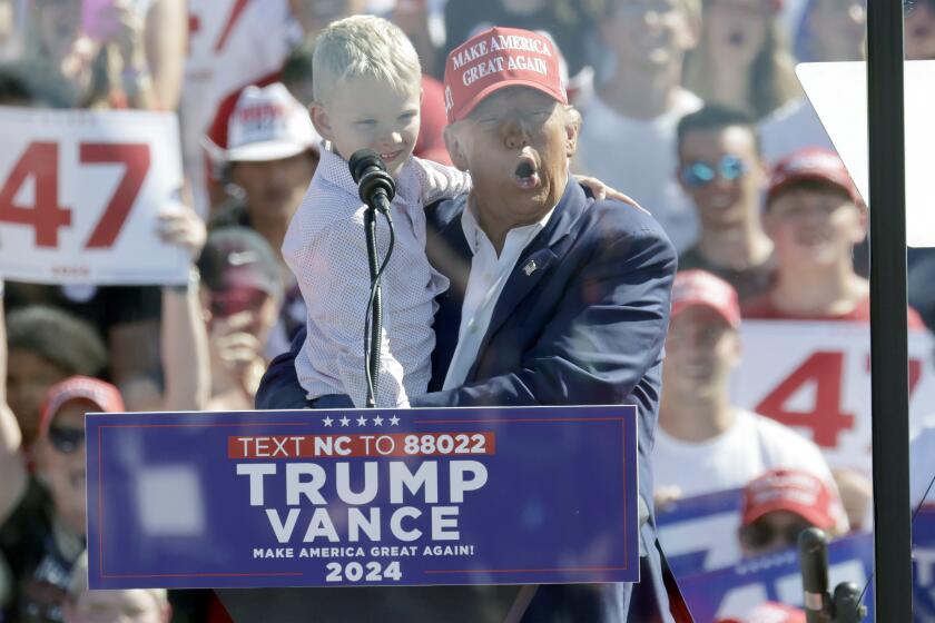 Republican presidential nominee former President Donald Trump holds his grandson Luke Trump as he speaks at a campaign event at Wilmington International Airport in Wilmington, N.C., Saturday, Sept. 21, 2024. (AP Photo/Chris Seward)