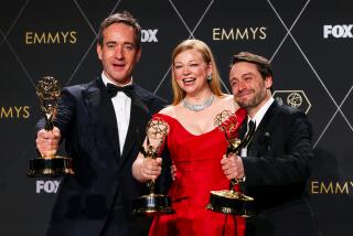 Three actors hold awards and smile for the camera.