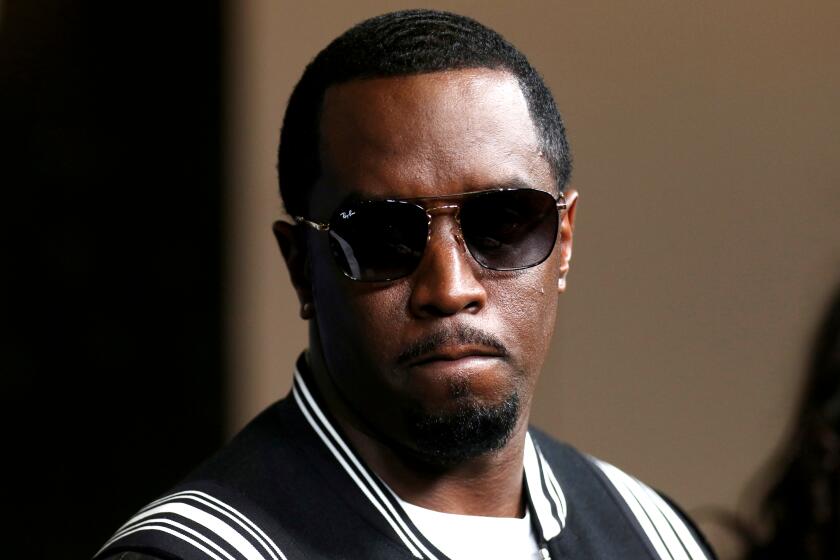 Sean "Diddy" Combs in big sunglasses and a black letterman jacket 