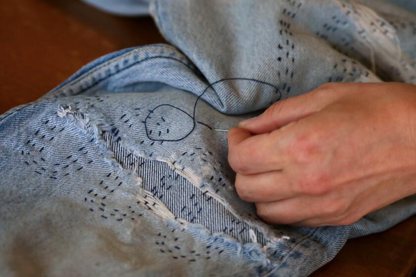 Kim Krempien, co-owner of Other Lives Studio, uses various sewing techniques to mend weathered jeans.
