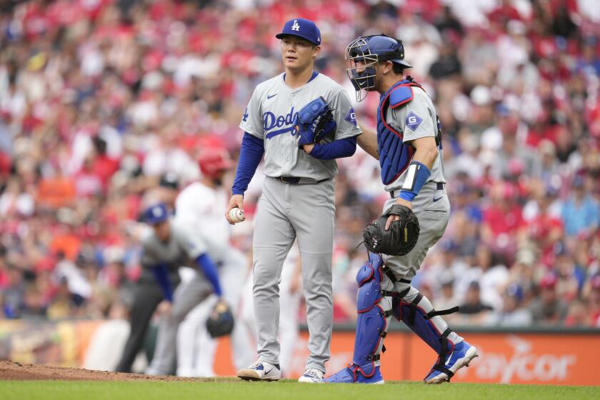 Dodgers catcher Austin Barnes taps pitcher Yoshinobu Yamamoto on the back and speaks with him during a game 