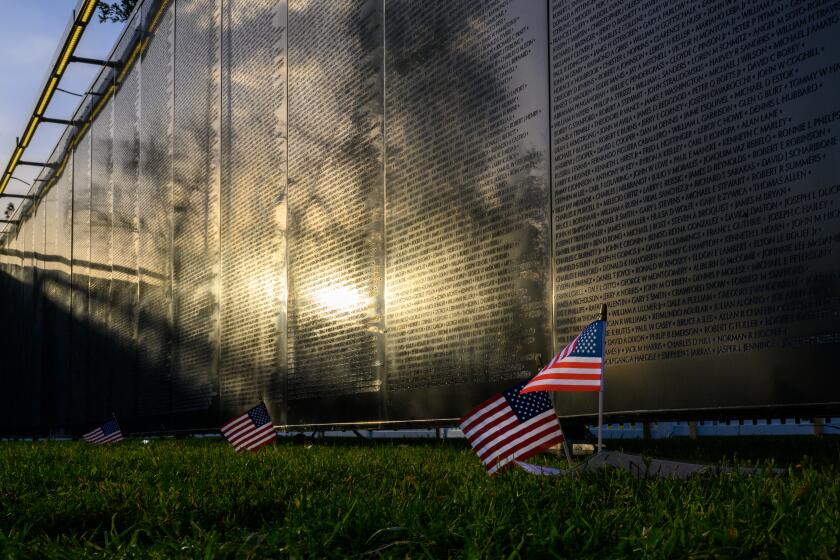 BALDWIN PARK, CA - MARCH 14, 2024: Small flags have been placed in front of The Wall That Heals, a replica of the Vietnam Veterans Memorial, to memorialize locals killed in the Vietnam War on display at Morgan Park on March 14, 2024 in Baldwin Park, California. The Wall That Heals is on a nationwide tour with it's first stop in Baldwin Park until March 17.(Gina Ferazzi / Los Angeles Times)