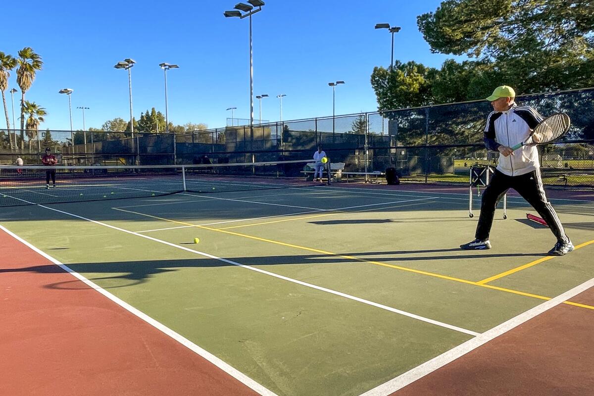 A man swings a tennis racket on a tennis court. 