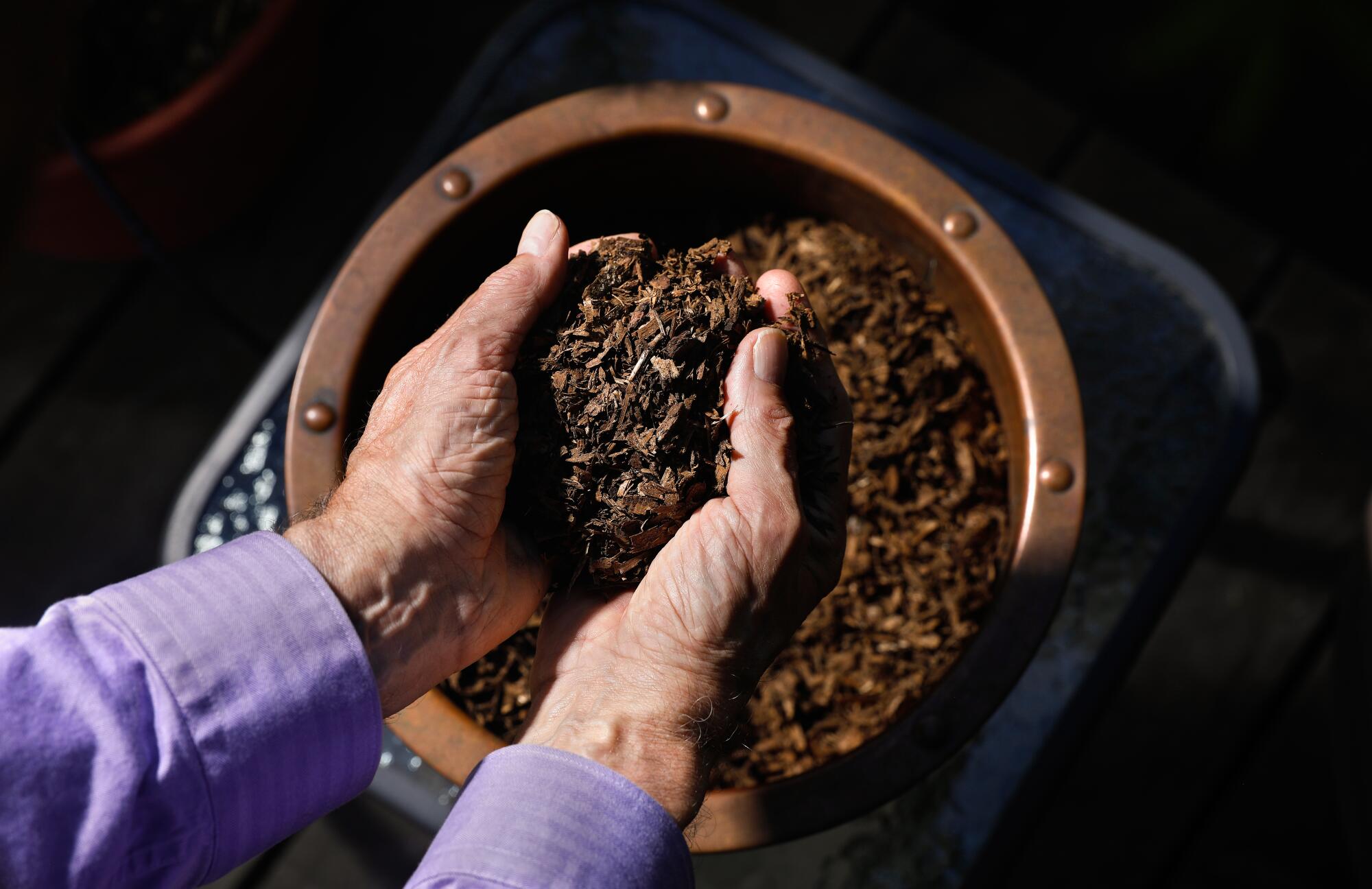 Larry Kreisman picks up a handful of soil from his late husband Wayne Dodge, who died in 2021.