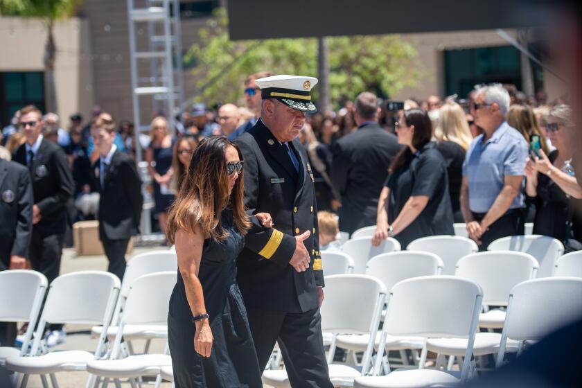 The fire chief walks with Kim Pontious, Andrew's wife at the memorial service.