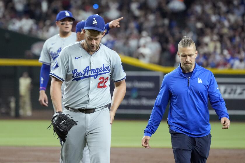 Los Angeles Dodgers starting pitcher Clayton Kershaw (22) walks off the field with head athletic trainer.