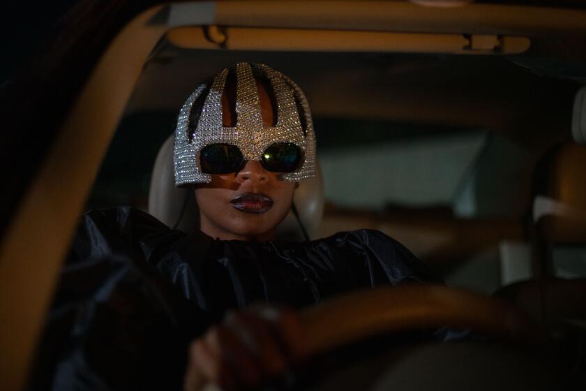 A woman in a sparkly headpiece sits in her car.