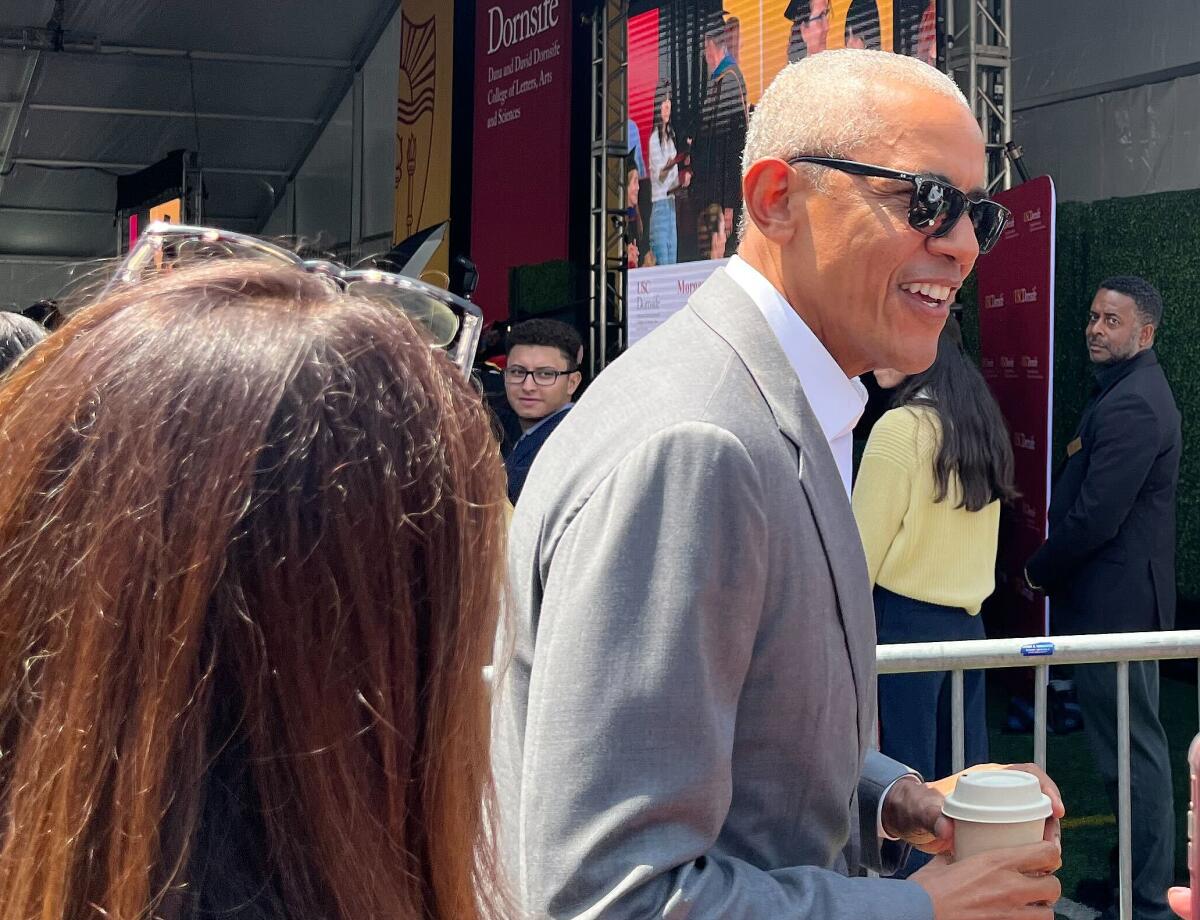 Former President Obama walks among a crowd during a USC graduation.