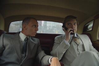 Two men drive in the back seat of a limo.