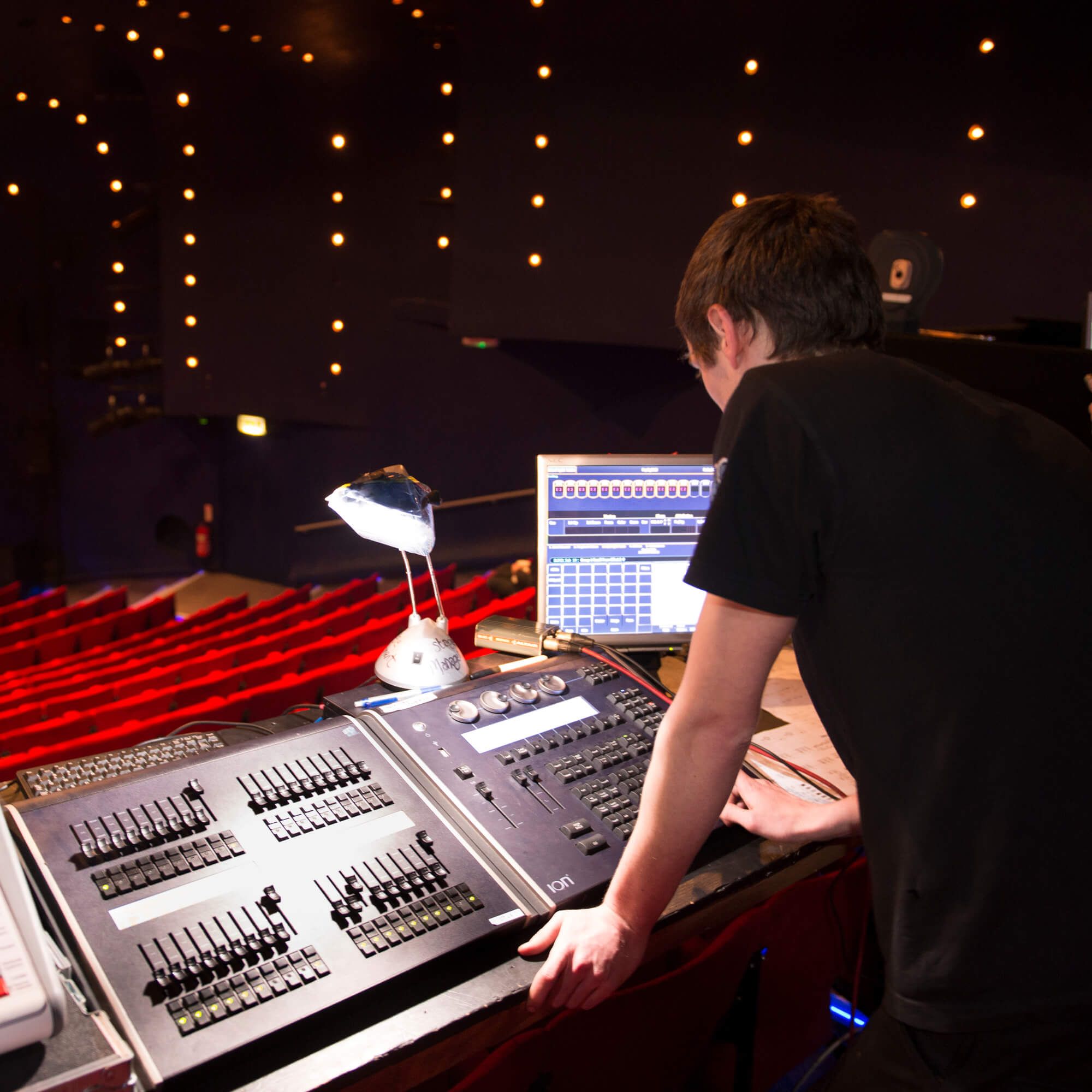 A technical theatre student works on sound equipment in the theatre