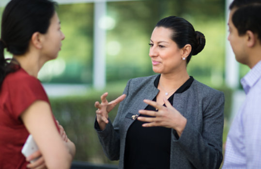 Three people having a discussion outside of an office building.