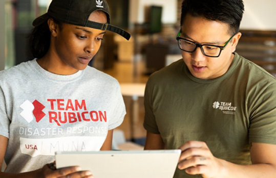 Membros da Team Rubicon olhando para um tablet juntos.