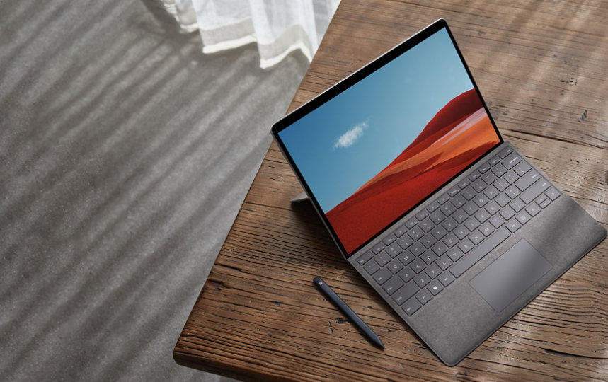 Surface Pro X on a desk with Surface Earbuds and a Surface Slim pen.