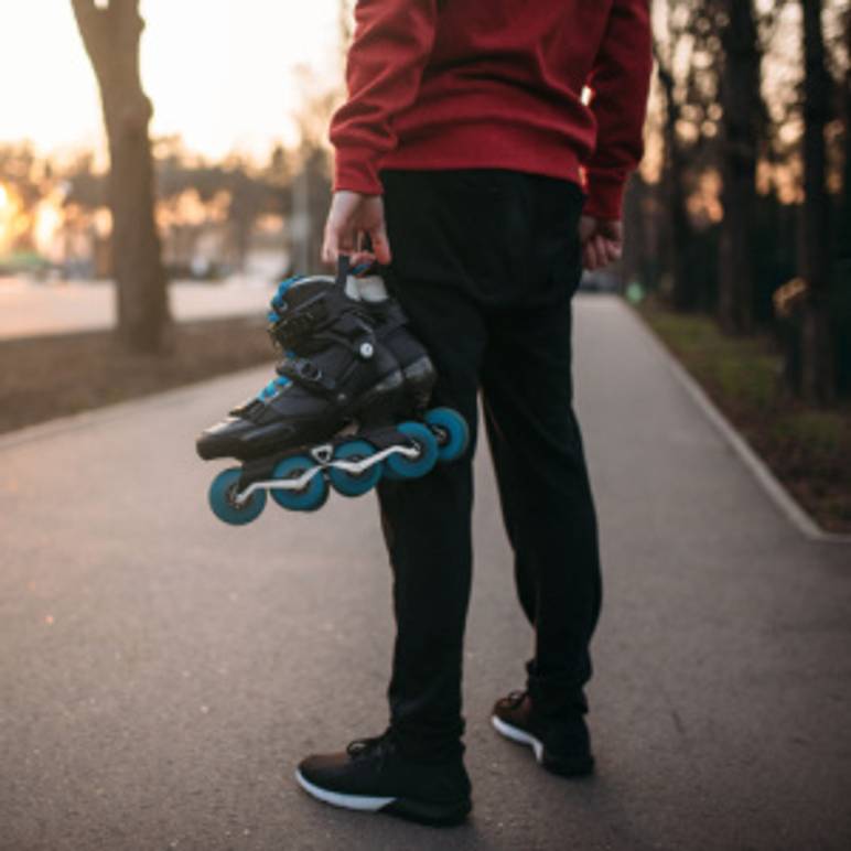 mann haelt inline-skates in hand