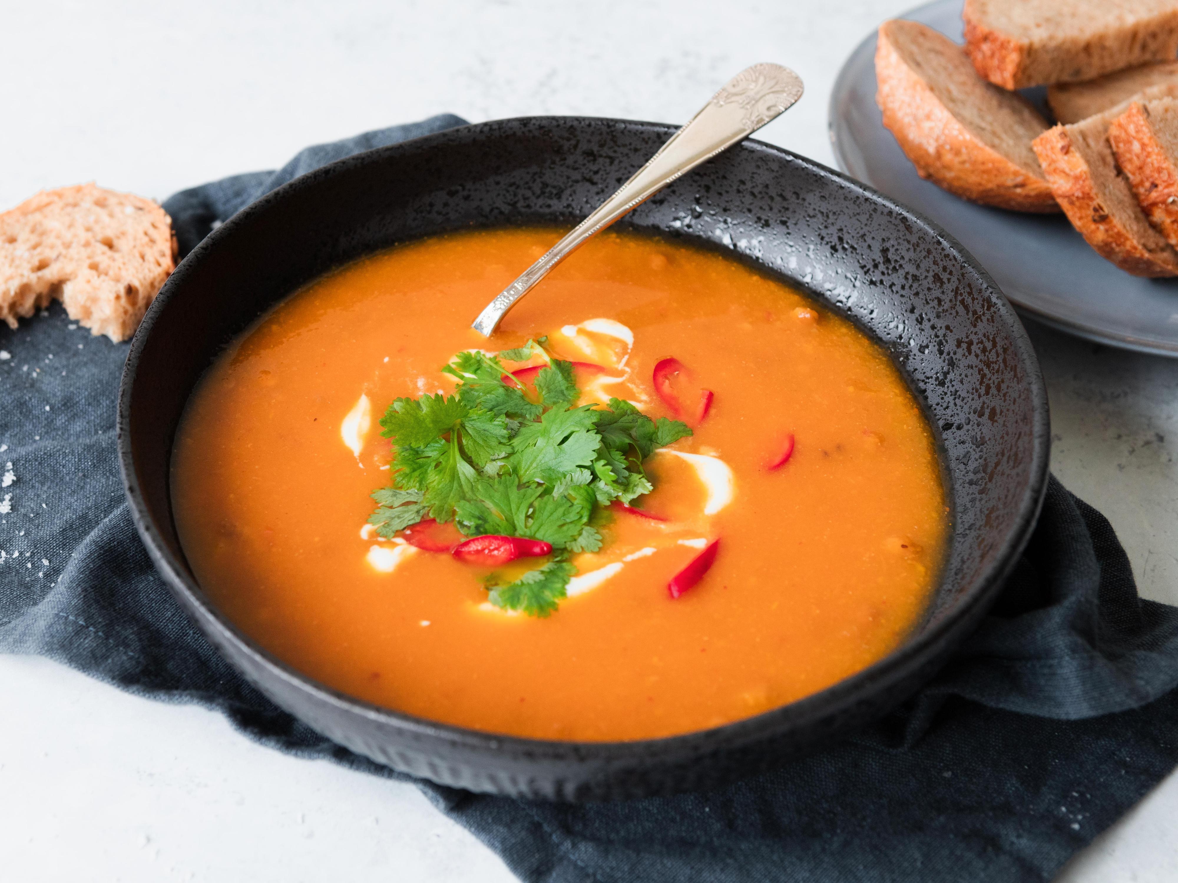 Gulrotsuppe med linser i skål toppet med koriander, créme fraîche og skiver med chili