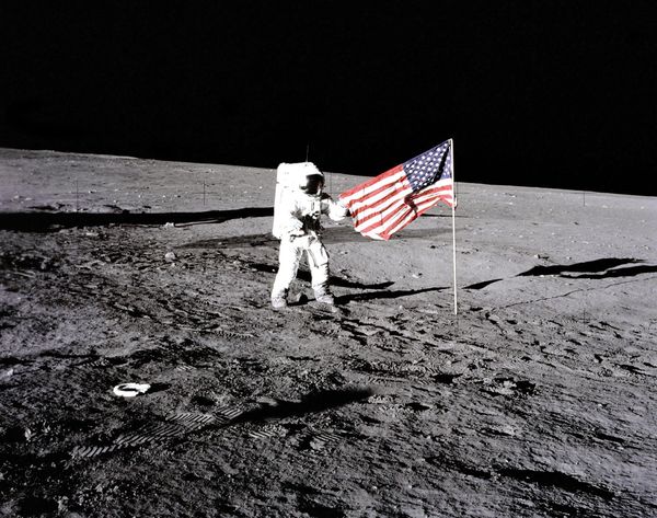 Apollo 12 astronaut Charles &quot;Pete&quot; Conrad stands beside the U.S. flag after is was unfurled on the lunar surface during the first extravehicular activity (EVA-1) Nov. 19, 1969. Footprints made by the crew can be seen in the photograph.