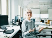 Ältere Frau in einem Büro. Ältere Arbeitnehmer können von Hinzuverdienst bei Rente profitieren.