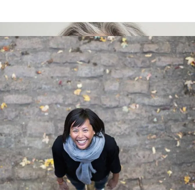 A woman standing in front of a brick wall.