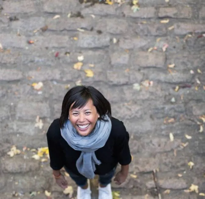 A woman standing in front of a brick wall.