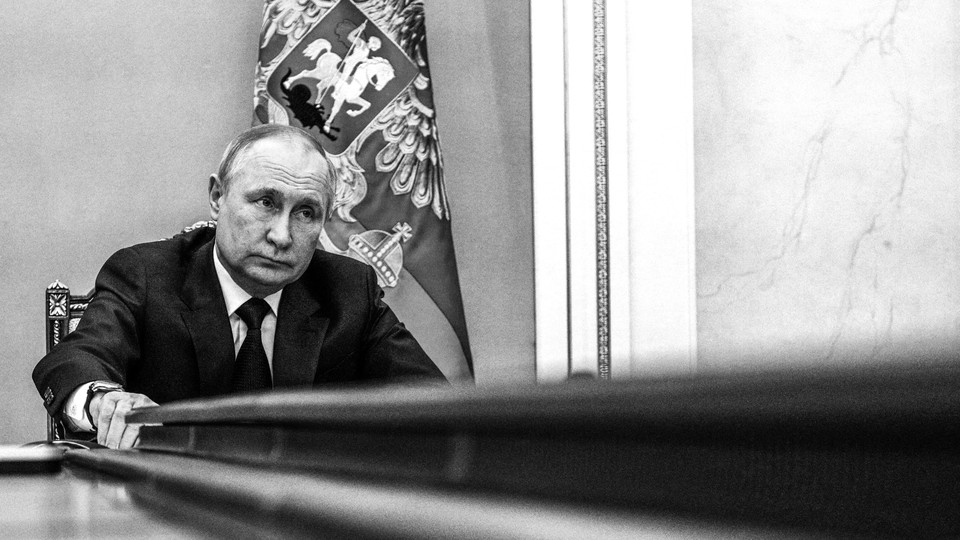 Vladimir Putin sitting at the end of a long table