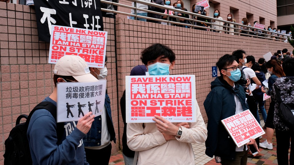 Medical workers in Hong Kong protest with red and white signs that say "Save HK now."