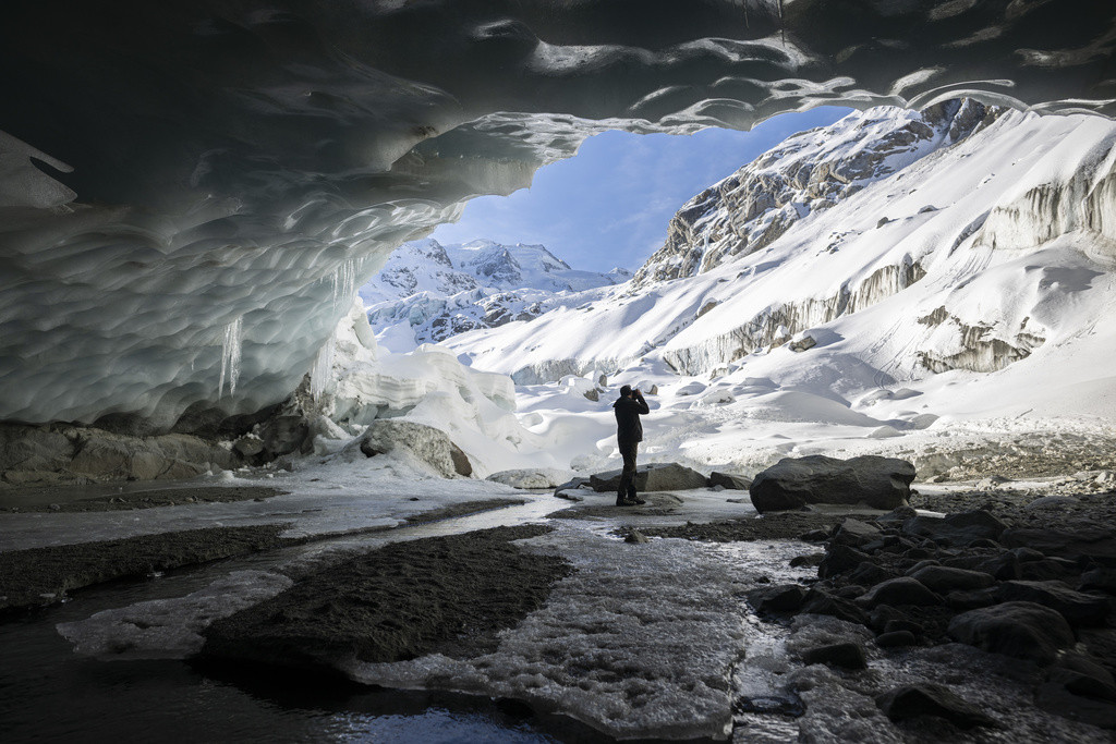 Ein Fotograf macht ein Bild in einer Gletscherhoehle am Morteratschgletscher, aufgenommen am Sonntag, 18. Februar 2024, in Pontresina. (KEYSTONE/Gian Ehrenzeller) View of a glacial cave in the Morteratsch glacier, pictured on Sunday, February 18, 2024, in Pontresina, Switzerland. (KEYSTONE/Gian Ehrenzeller)