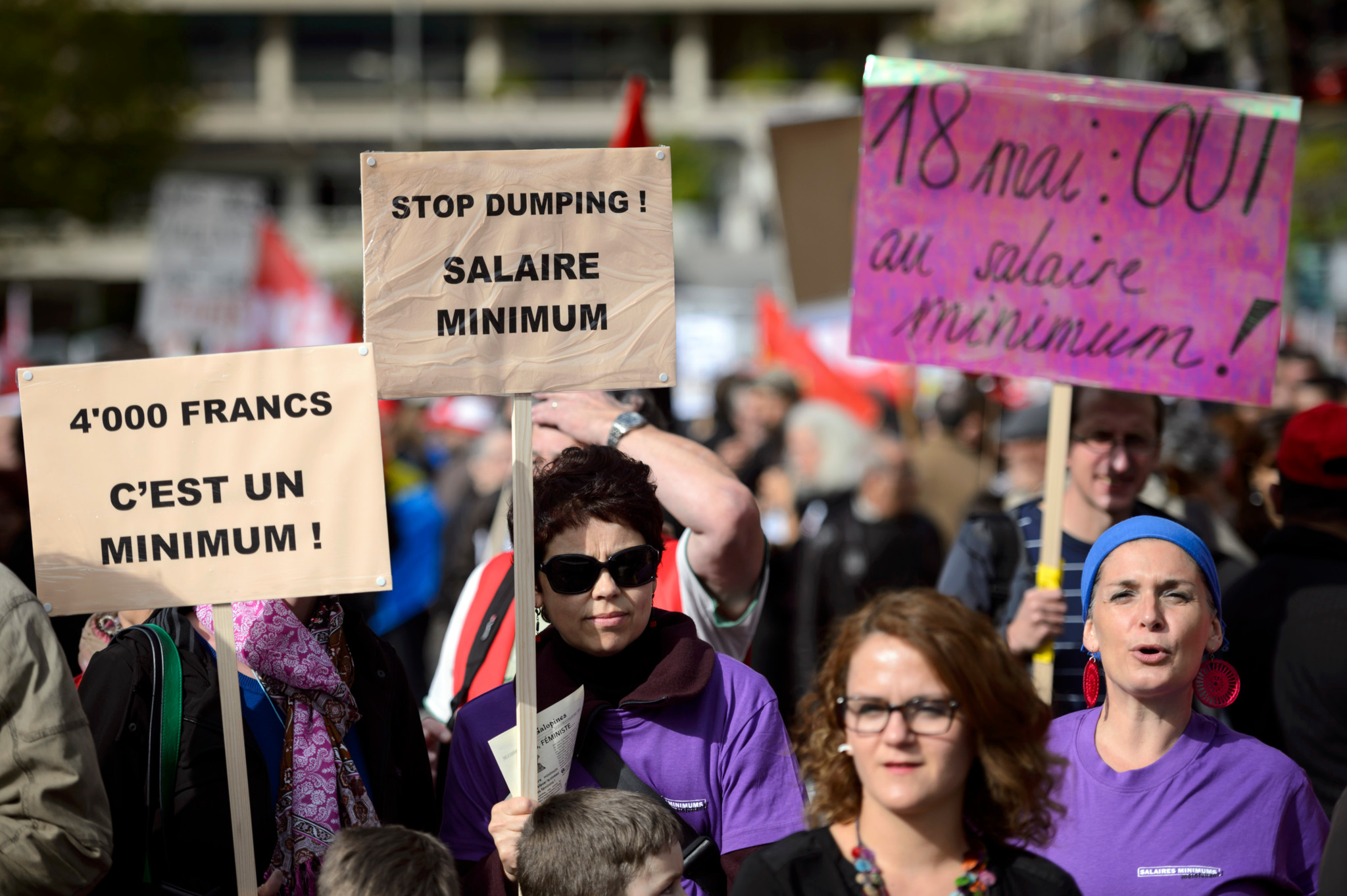 Des personnes defilent avec des banderoles pour l' initiative sur le salaire minimum a 4000frs lors de la manifestation du 1er Mai, la fete du travail, ce mercredi 1 mai 2014 dans les rues de Lausanne. (KEYSTONE/Laurent Gillieron)