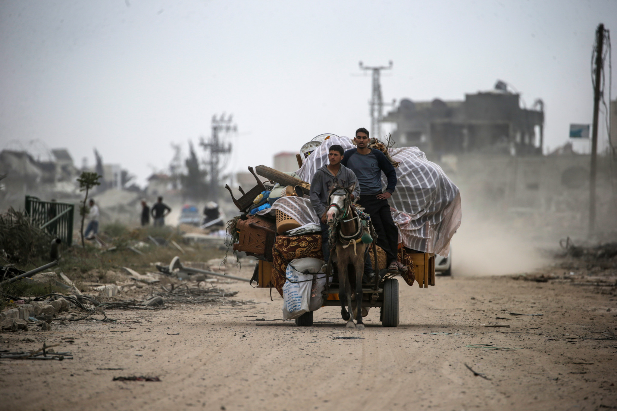 epa11265898 Palestinians ride on a cart loaded with their belongings past the rubble of destroyed houses following the Israeli military operation in Khan Younis, southern Gaza Strip, 08 April 2024. Displaced Palestinians have started to return to Khan Younis, after the Israeli army announced on 07 April its partial withdrawal from parts of the southern Gaza Strip. Since 07 October 2023, up to 1.9 million people, or more than 85 percent of the population, have been displaced throughout the Gaza Strip, some more than once, according to the United Nations Relief and Works Agency for Palestine Refugees in the Near East (UNRWA), which added that most civilians in Gaza are in 'desperate need of humanitarian assistance and protection'.  EPA/MOHAMMED SABER