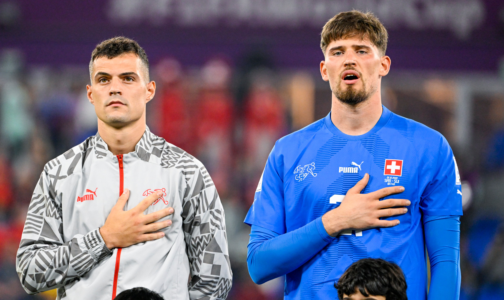 Zwei Schweizer Fussballspieler stehen nebeneinander und halten während der Nationalhymne ihre rechte Hand auf der Brust.