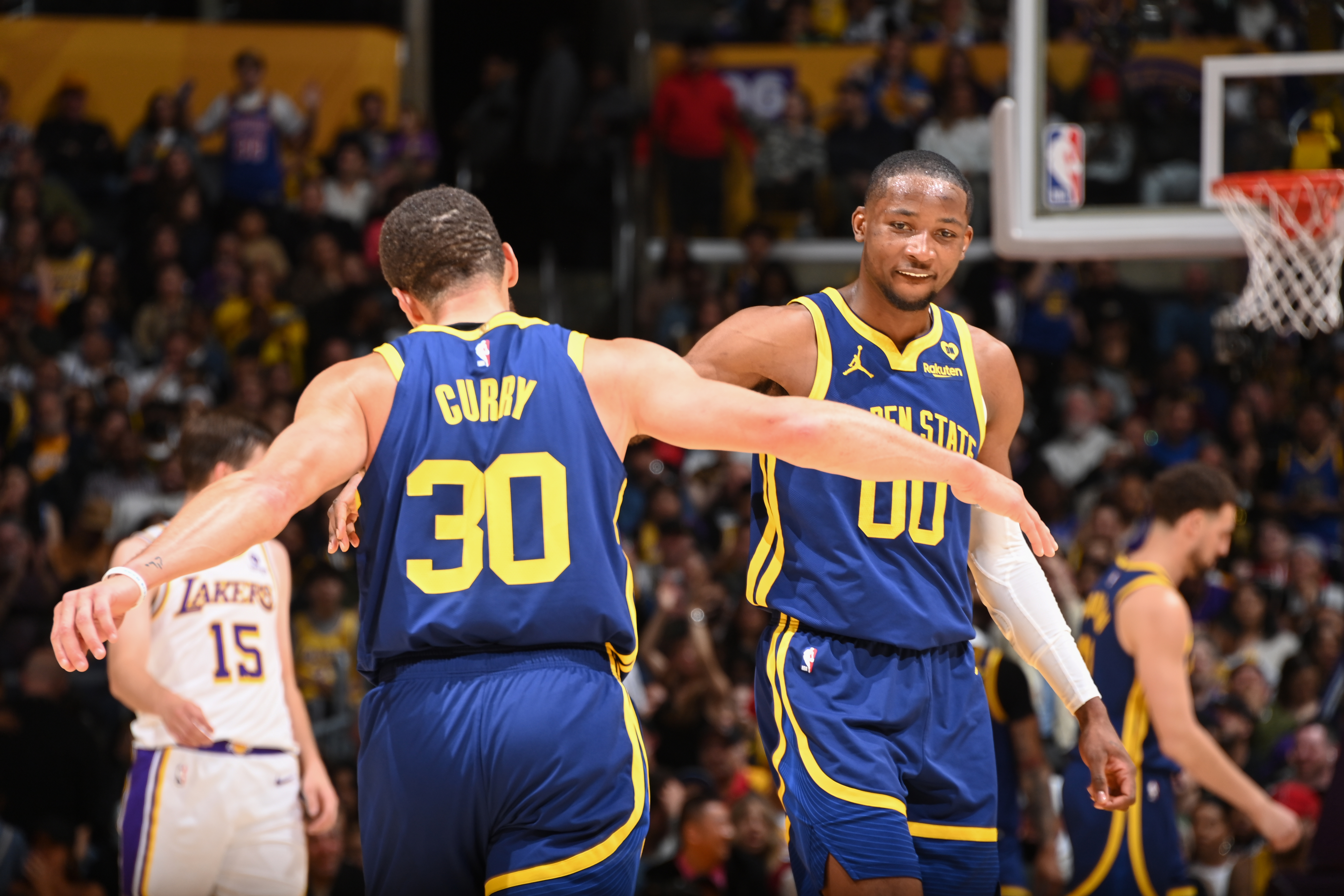 Steph Curry high-fiving Jonathan Kuminga at center court. 