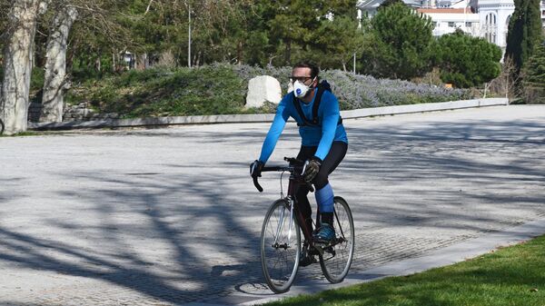 Мужчина на велосипеде в защитной маске парке Каса-де-Кампо в Мадриде
