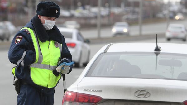 Сотрудник полиции в защитной маске во время специальных мероприятий МВД и Росгвардии по оповещению водителей о необходимости соблюдения правил самоизоляции