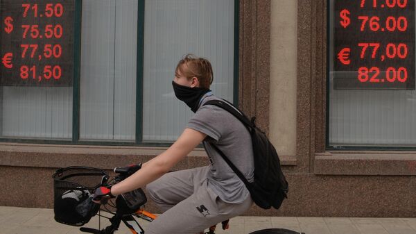 Молодой человек на велосипеде у информационных табло с курсом валют на Тверской улице в Москве
