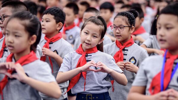 Учащиеся начальной школы во время церемонии поднятия флага в первый день нового семестра в Шэньяне, провинции Ляонин