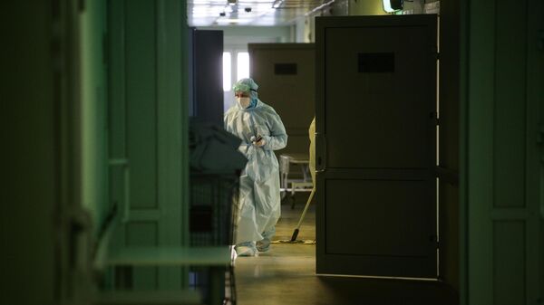 Медик в защитном противоэпидемическом костюме идет по коридору Новосибирской областной клинической больницы