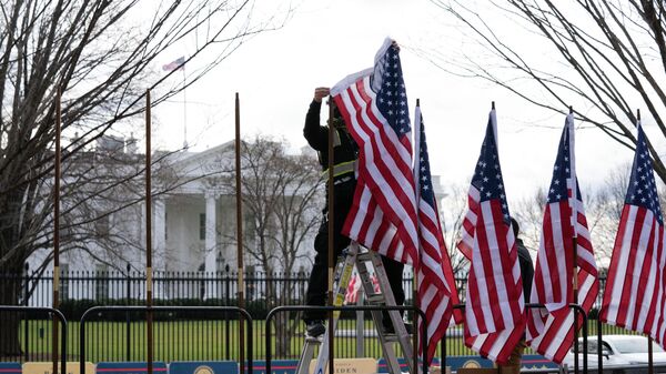 Рабочий устанавливает флаги возле Белого дома в Вашингтоне