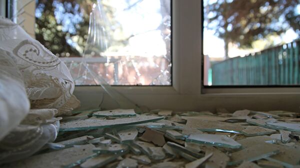 Разбитое окно дома, поврежденное разрывом снаряда в результате обстрела в Петровском районе Донецка