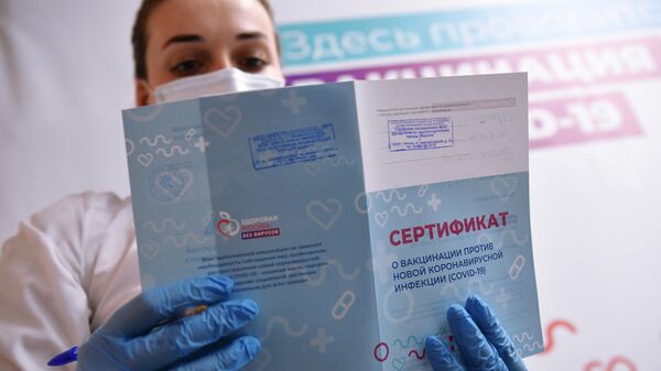 Медицинский работник держит в руках сертификат о вакцинации в мобильном пункте вакцинации от COVID-19 в торговом центре Арена Плаза в Москве