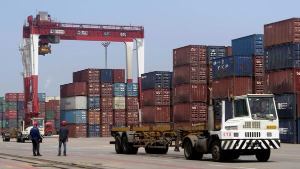 Грузовик проезжает мимо транспортных контейнеров в порту Инкоу в провинции Ляонин на северо-востоке Китая