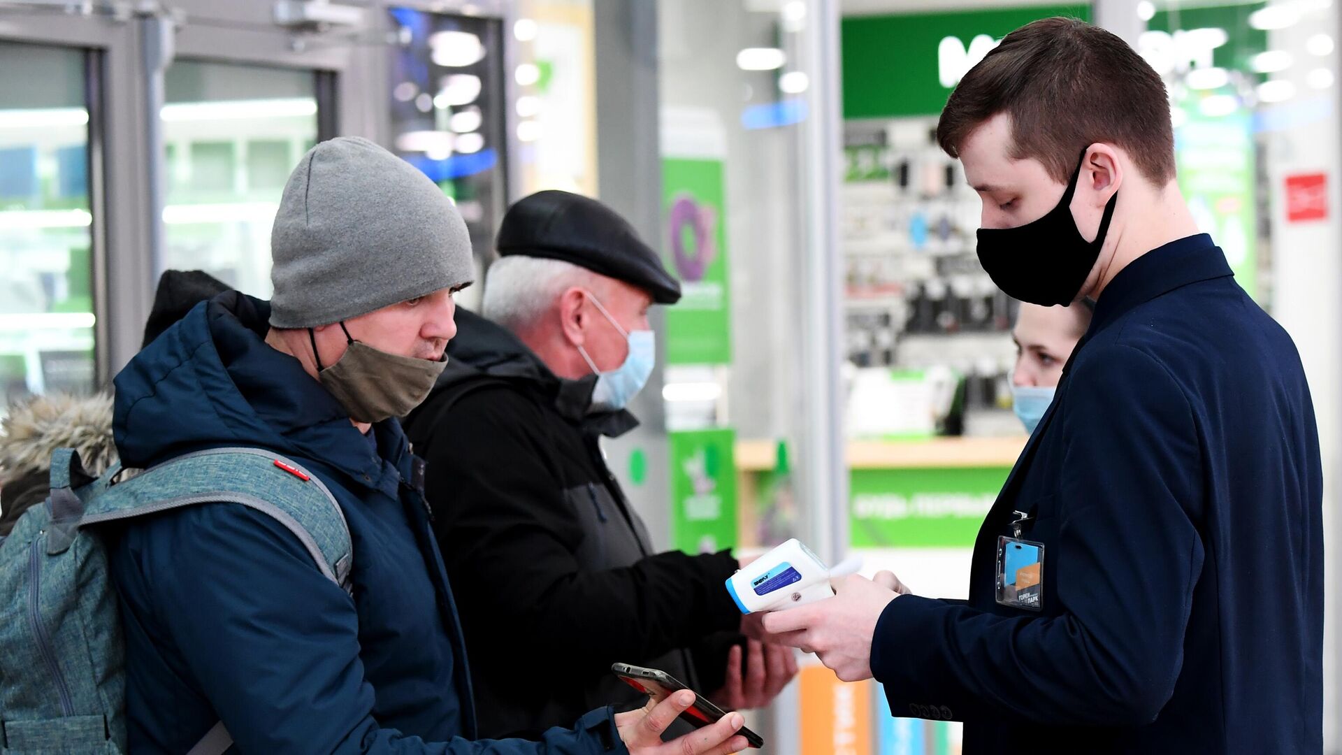 Сотрудник службы безопасности проверяет наличие у посетителей QR-кодов на входе в торговый центр - РИА Новости, 1920, 22.10.2021